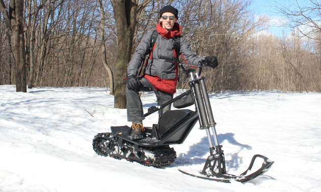 A man poses on an electric snow scooter.