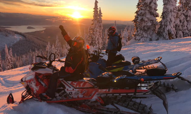 David Norona fist-pumps on his snowmobile as the sun sets in the distance.