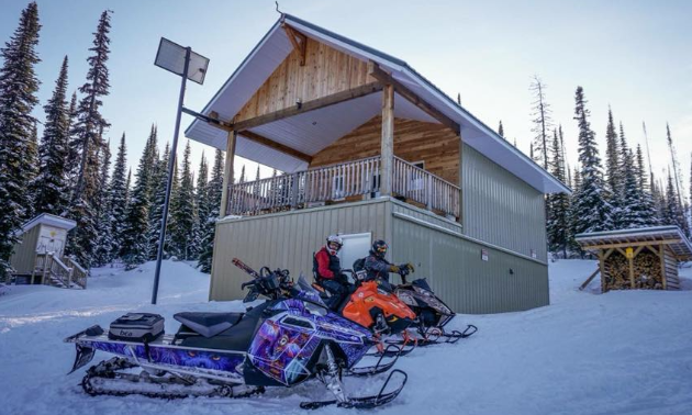 Two snowmobilers park in front of the Rolling Hills Cabin in Fernie.