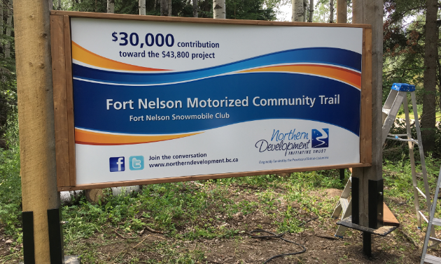 A government sign explaining how the Fort Nelson Snowmobile Club made its upgrades to its trail system.