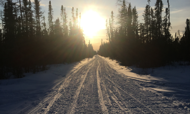 The sunrise comes up over the snowmobile trail. 