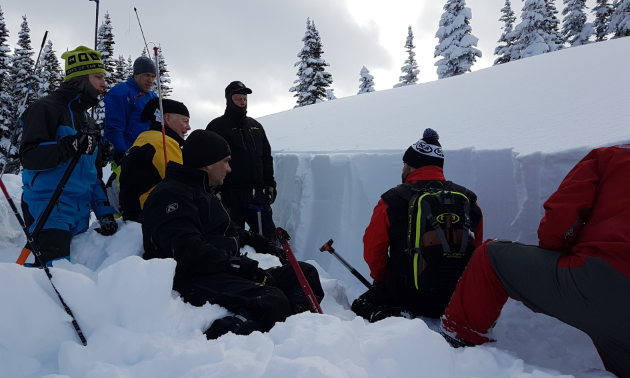 Curtis Pawliuk instructs a group of students how to work in a snow profile.