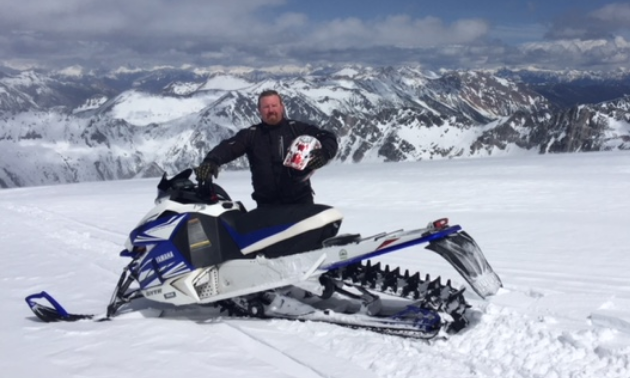 Gary Prosser poses with his snowmobile on a mountain in Radium Hot Springs. 