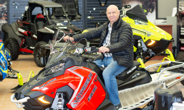 Gerry Dolezsar sits on a snowmobile in a store. 