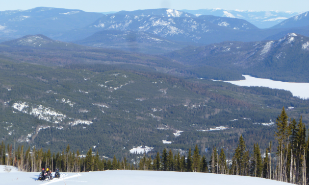 Snowmobilers ascend Hendrix Mountain and look into the valley below.