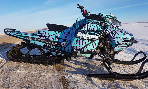 A turquoise and purple snowmobile.