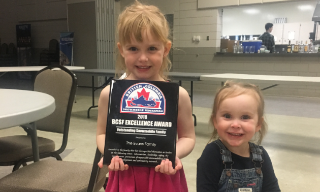 The Evans family won the Excellence Award for Outstanding Snowmobile Family by the British Columbia Snowmobile Federation. Five-year-old Paisley and two-year-old Brooklyn are happy to show off the award.