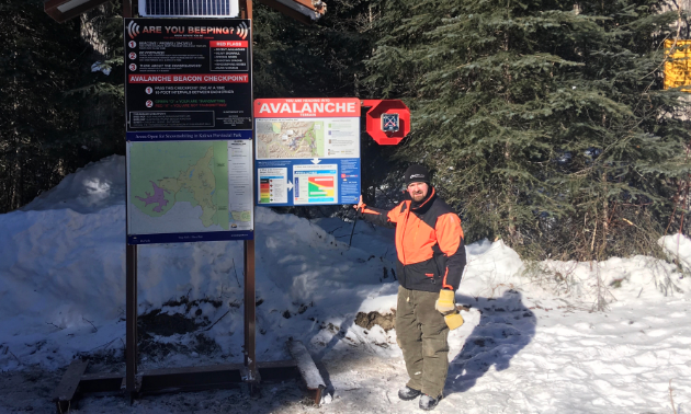 Les L’Heureux stands next to a solar-powered transceiver checker, complete with parks signage and avalanche awareness.