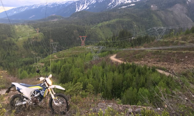 A dirt bike is parked on top of a big mountain.