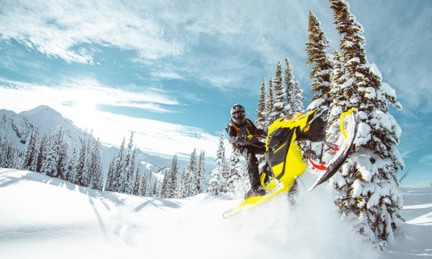 A snowmobiler gets air on a yellow Ski-Doo Summit 850 E-TEC.