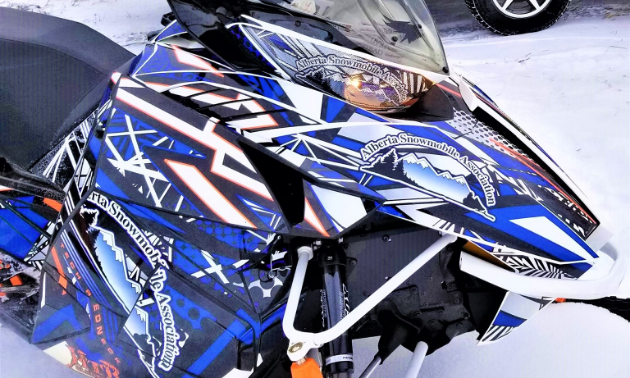 A blue snowmobile with white and orange designs along its exterior.