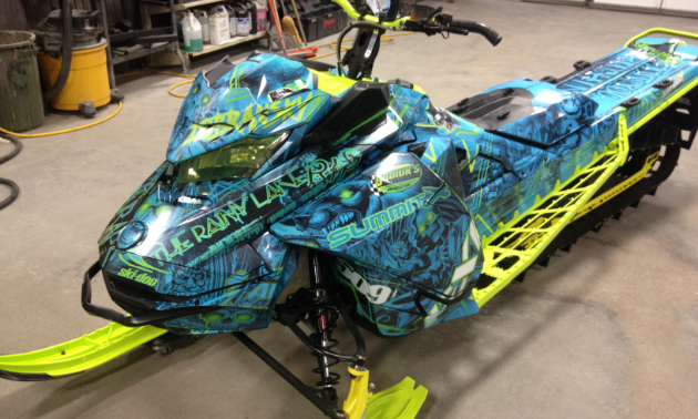 A beautiful blue sled wrap lined with neon green on a snowmobile.