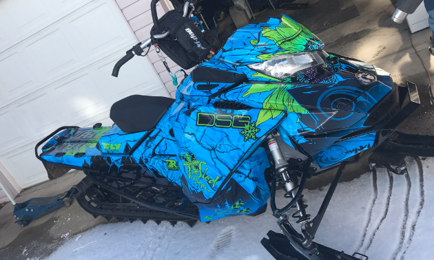 A blue and green sled wrap on a snowmobile.