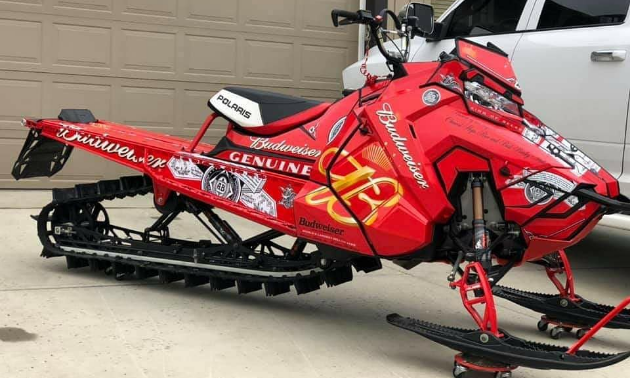 A red sled wrap on a snowmobile that says Budweiser.
