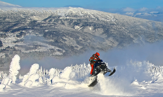 A snowmobiler ascends a mountain to climb out of a bowl of snow.