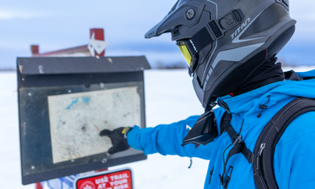 A snowmobiler points to a trail map.