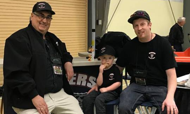 Stan Langley sits at a booth with a man and a child.