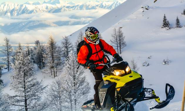 A snowmobiler ascends a mountain on his sled.