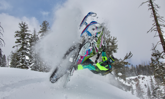 A snowmobiler does a backflip in the snow. 