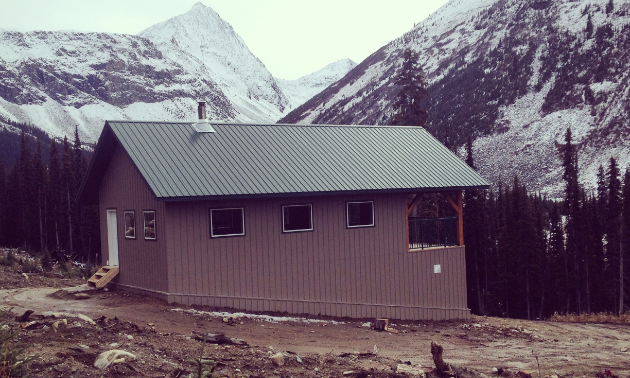 A beige warm-up shelter is settled within a mountain range.