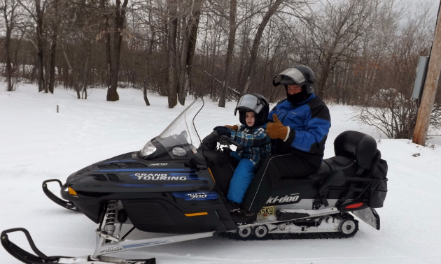 Barry Malcolm takes his grandson, Grayson, out for rides on his snowmobile.