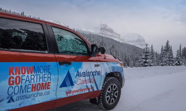 Avalanche Canada's truck is parked next to a snowy road