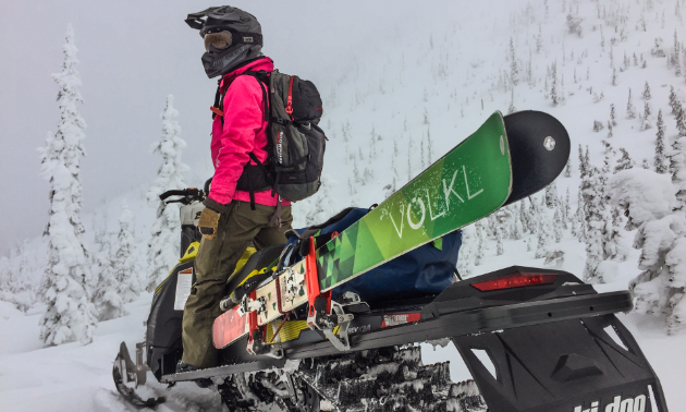 Jennifer Coulter stands on her snowmobile, looking into the distance