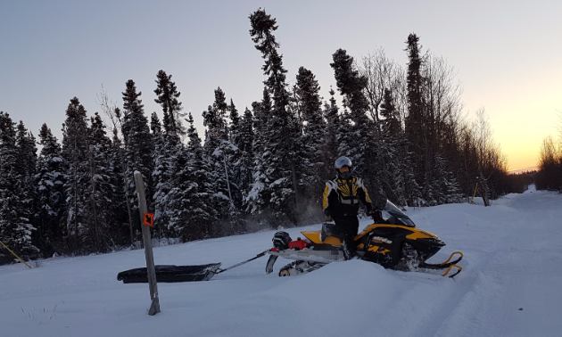 Kelly Martens poses on his snowmobile next to a trail