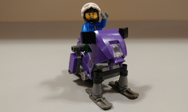 A happy sledder rides a Lego snowmobile