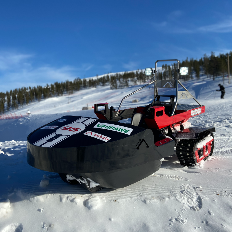 A black Bobsla electric snowmobile is parked on snow. 