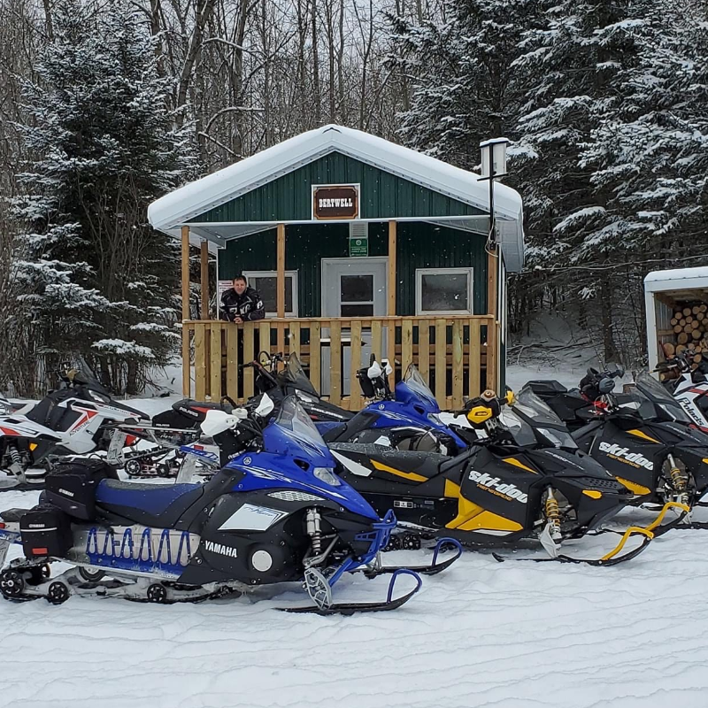 A line of snowmobiles in front of the green Bertwell warm-up shelter in Hudson Bay, Saskatchewan.