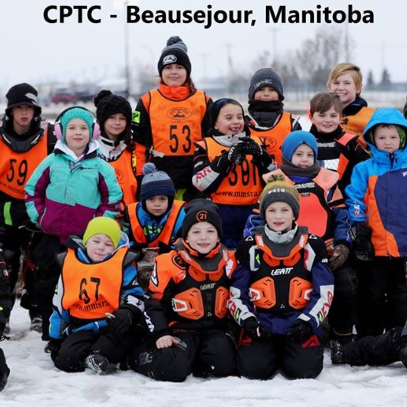 A group of children wearing orange pinnies overtop of winter clothing are part of the 2019-2020 Manitoba Mini-Sled Racer’s Association.