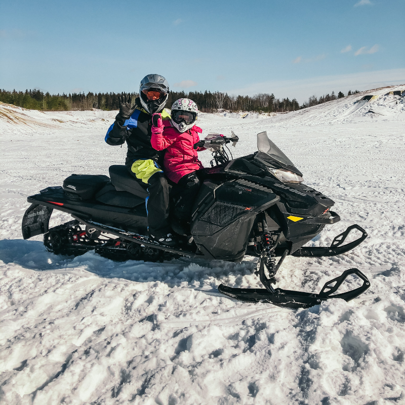 A man and little girl ride a black snowmobile on the plains in Manitoba. 