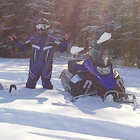 snowmobiler standing beside a sled in deep snow