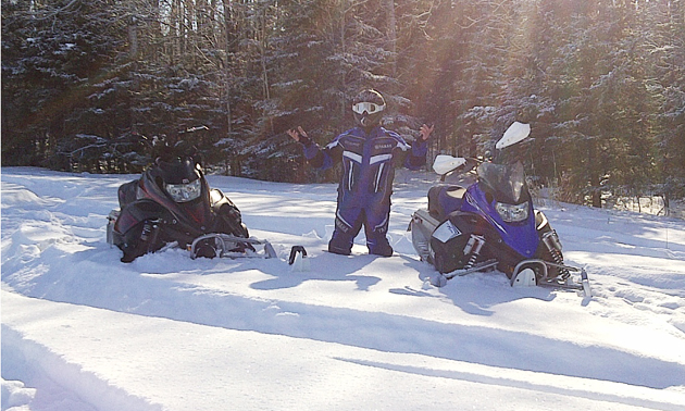 snowmobiler standing beside a sled in deep snow