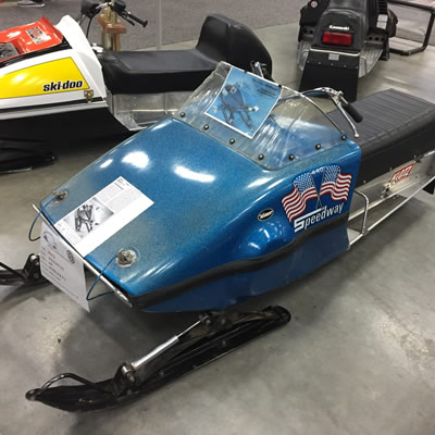 Speedway snowmobile, painted metallic blue in colour, with crossed American flags logo and 'Speedway' painted on side. 