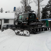 A snowmobile trail groomer is sitting in front of the Pepper Hill Cabin near Edson, Alberta.