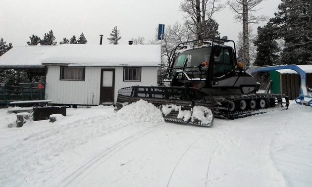 A snowmobile trail groomer is sitting in front of the Pepper Hill Cabin near Edson, Alberta.