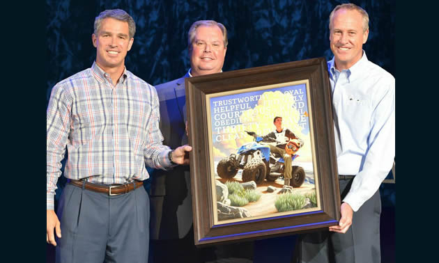 Three men presenting a boy scout picture