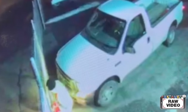 Screenshot of white truck and man breaking through gate. 