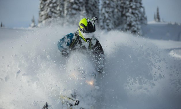 A sledder with a face and sled full of snow. 