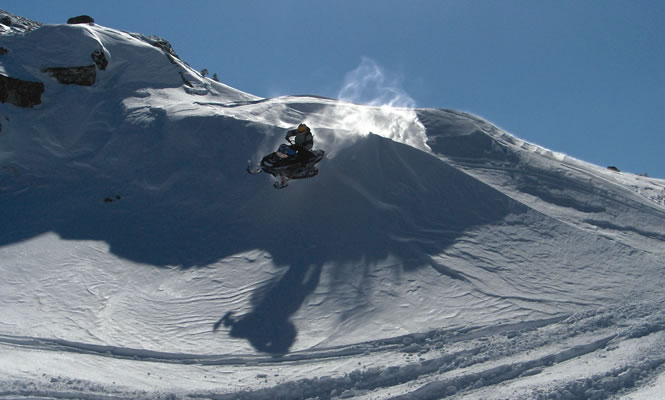 a sledder takes a leap over the crest of a hill