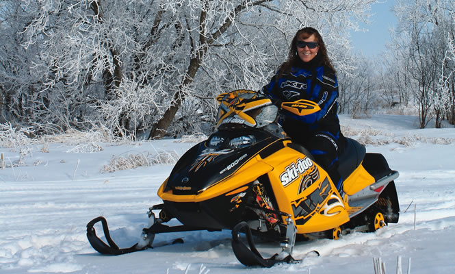 A woman sitting on her Ski-Doo in a snowy landscape