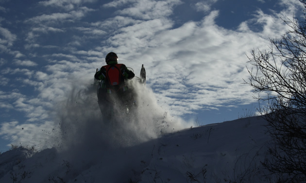 Erik catching some air on the Saskatoon Snowmobile Club's trails, while wearing a chest protector for safety.