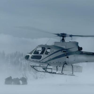 Still of sledders and helicopter in blizzard. 