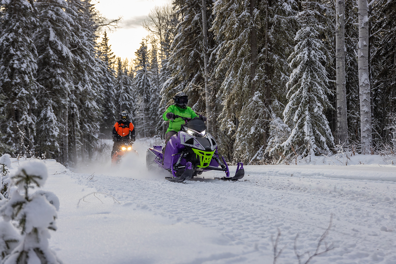Two snowmobilers cruise through a trail in Whitecourt, Alberta, in beautiful boreal forest