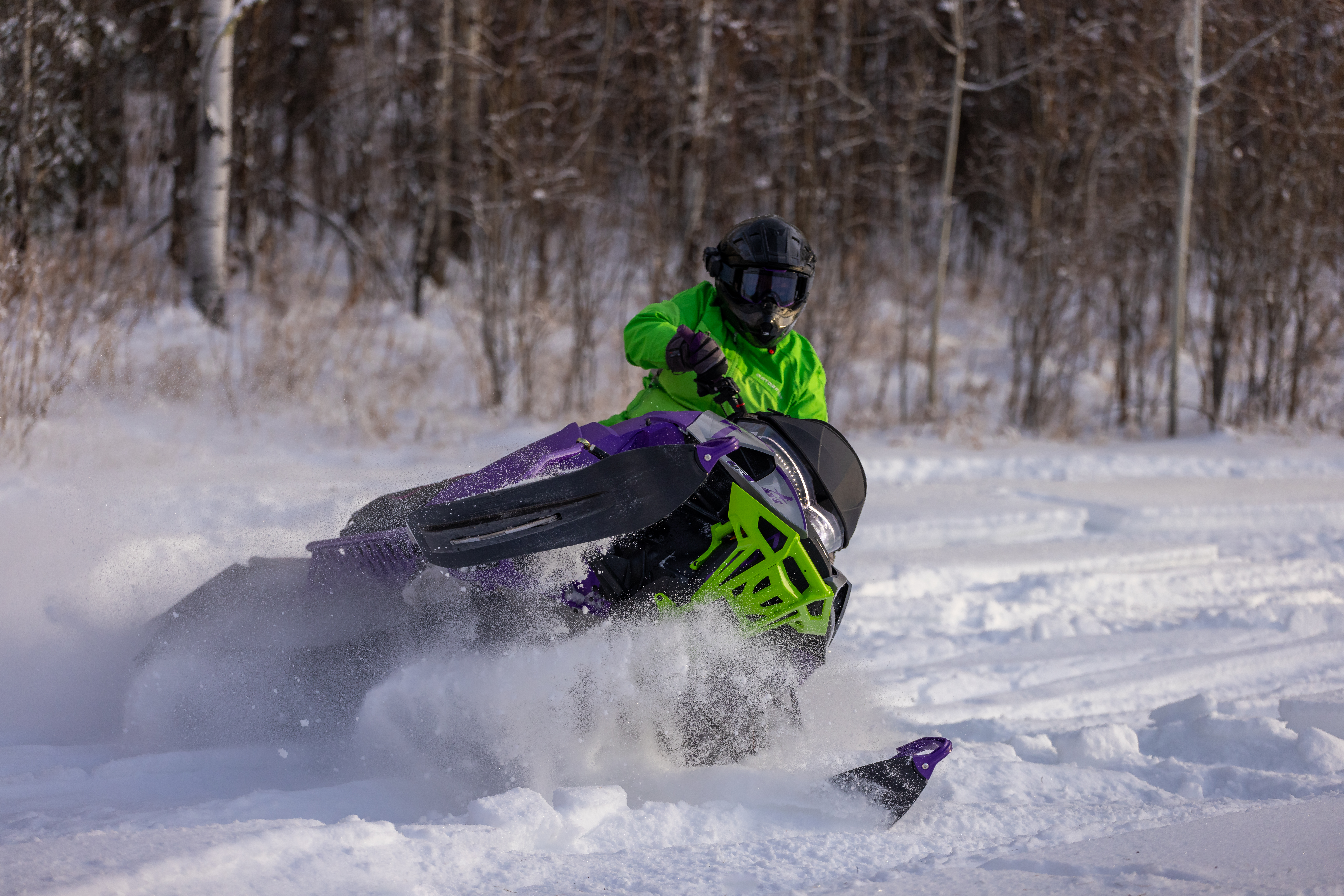A snowmobiler cuts into the snow on a sharp turn
