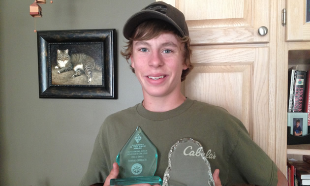Teenage boy wearing a baseball cap and T-shirt holds two plexiglass awards