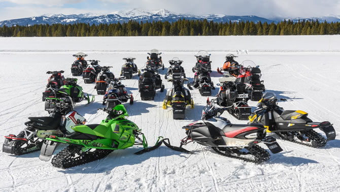Picture of a group of snowmobilers gathered together in a circle. 
