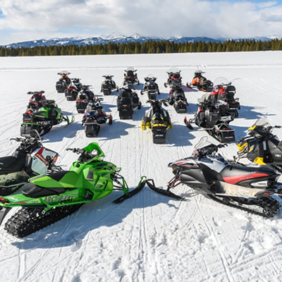 Group of sledders in a circle, with logo of the International Snowmobile Manufacturer's Association logo. 